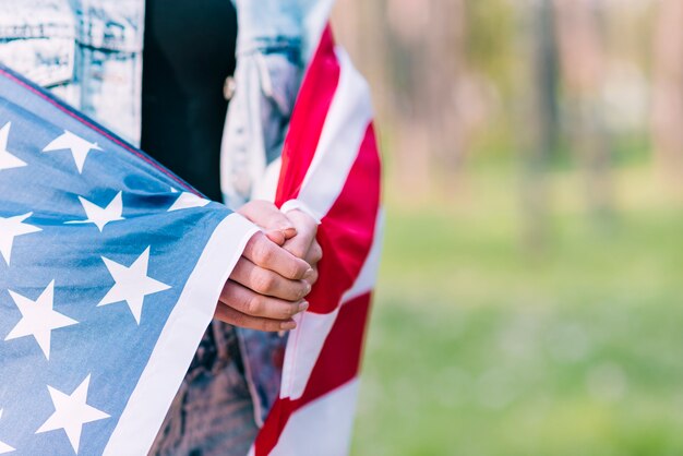 Fêmea anônima envolvendo na bandeira americana enquanto celebra o dia da independência