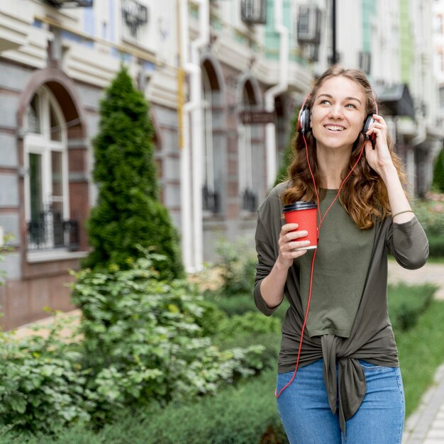 Fêmea com café e fones de ouvido