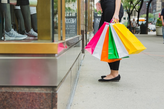 Fêmea com sacos de compras perto de vitrine