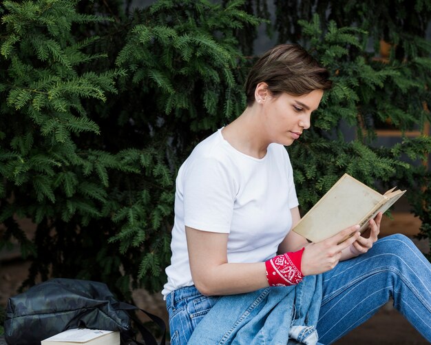 Fêmea de cabelos curtos que senta-se com o livro no parque
