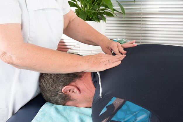 Fêmea de fisioterapeuta fazendo massagem nas costas no consultório médico