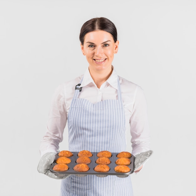 Fêmea do cozinheiro chefe de pastelaria que sorri com lata do queque