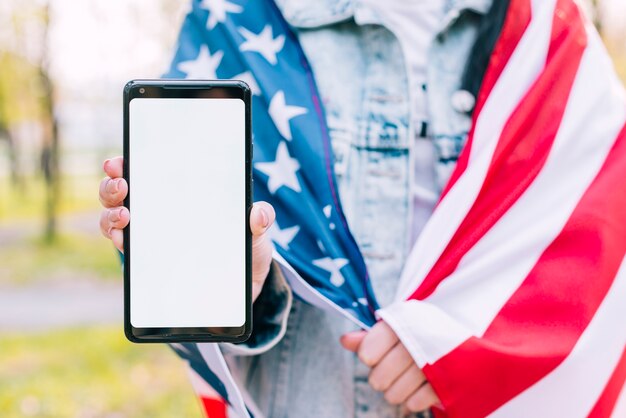 Fêmea, embrulhado, em, bandeira americana, segurando, telefone móvel