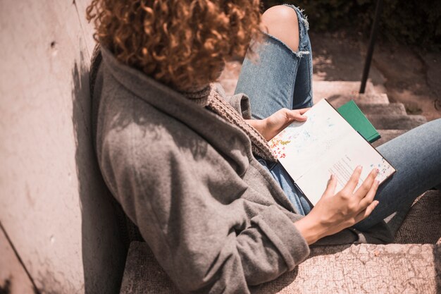 Fêmea jovem ruiva com livro na escada