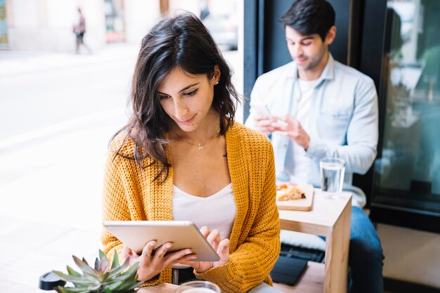 Fêmea no café trabalhando em tablet