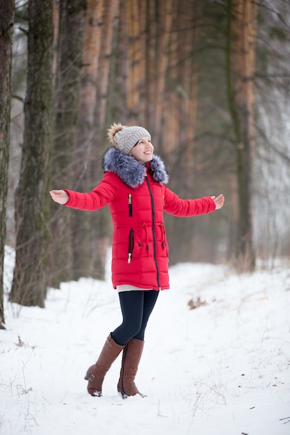 Fêmea sorridente feliz no casaco de inverno vermelho gozando ao ar livre