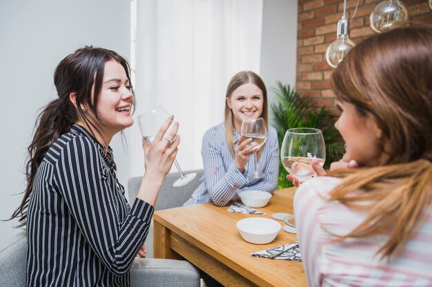 Fêmeas bebendo vinho e rindo em casa