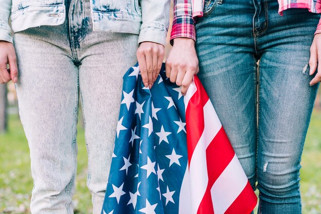 Fêmeas de colheita em jeans com bandeira americana