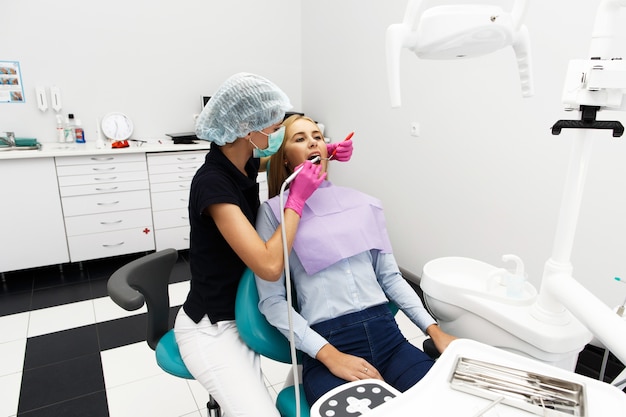 Feminino dentista que trata os dentes do paciente