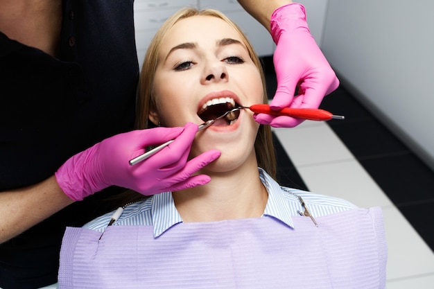 Feminino dentista que trata os dentes do paciente