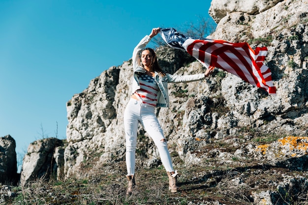 Feminino, levantando as mãos com bandeira na montanha