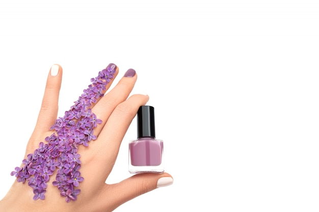 Feminino mão segurando a garrafa de esmalte roxo. Conceito de primavera.