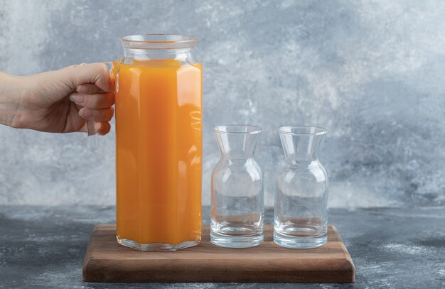 Feminino mão segurando a jarra de suco de laranja.