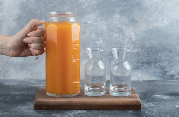 Feminino mão segurando a jarra de suco de laranja.