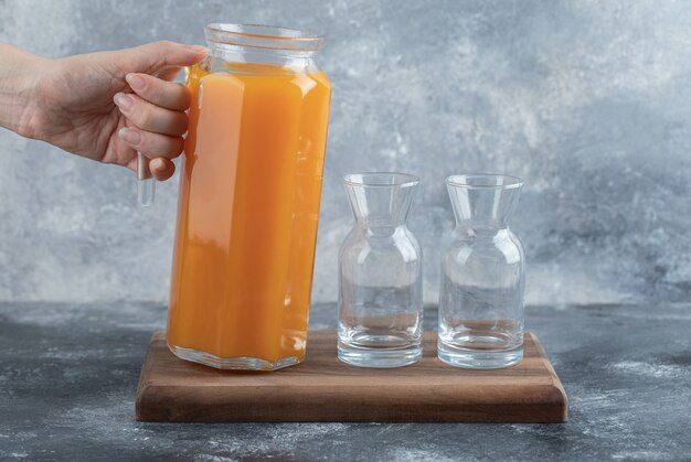 Feminino mão segurando a jarra de suco de laranja.