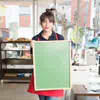 Foto grátis feminino segurando placa de menu verde em branco no café