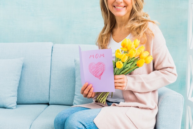 Foto grátis feminino sorrindo com tulipas e cartão postal para a mãe