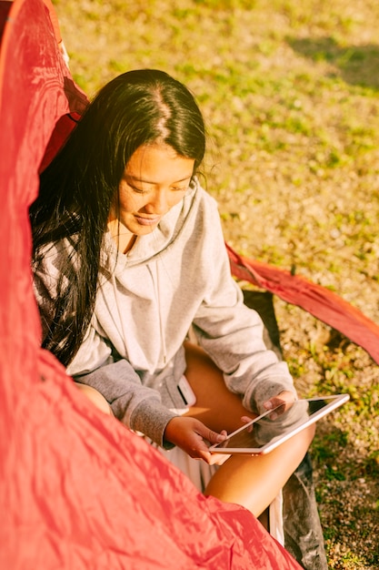 Feminino viajante com tablet sentado na tenda