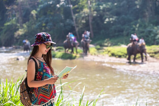 Femininos turistas na mão têm um mapa de viagem feliz.