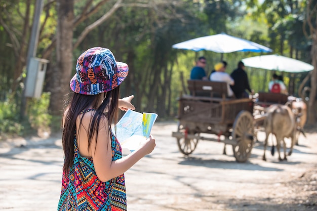 Femininos turistas na mão têm um mapa de viagem feliz.