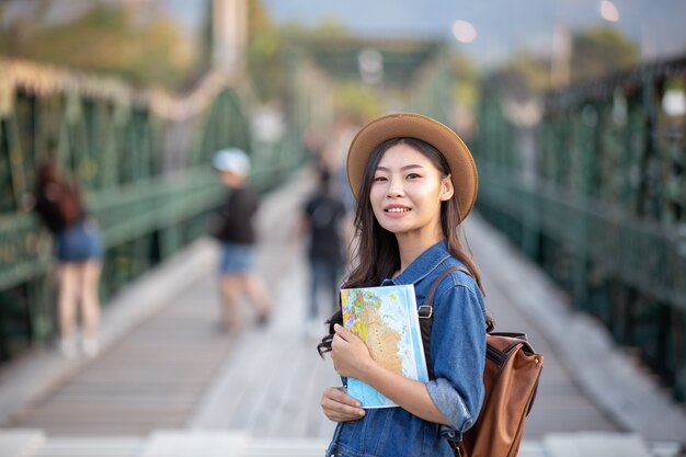 Femininos turistas na mão têm um mapa de viagem feliz.
