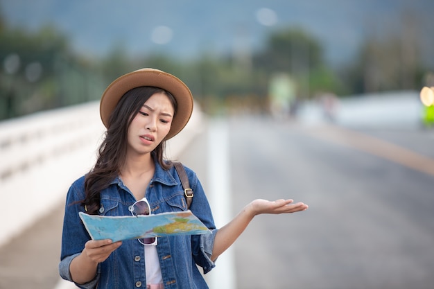 Femininos turistas na mão têm um mapa de viagem feliz.