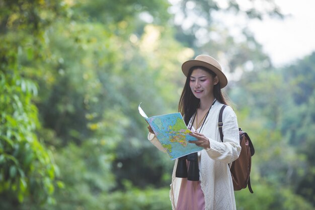 Femininos turistas na mão têm um mapa de viagem feliz.