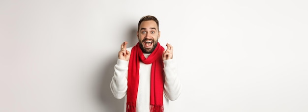 Foto grátis feriados de natal e conceito de ano novo homem esperançoso fazendo desejo com dedos cruzados esperando por gif