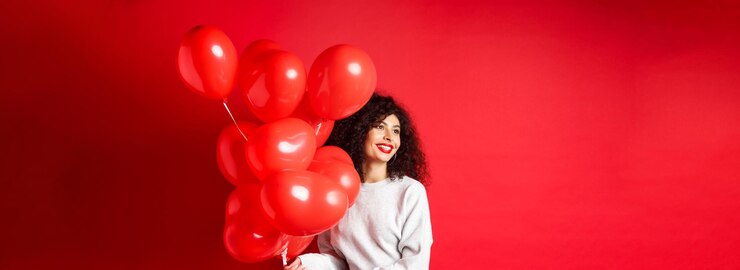 Foto grátis feriados e celebração mulher feliz posando com balões de festa em fundo vermelho olhando de lado para e