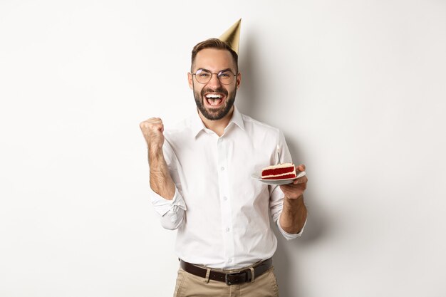 Feriados e comemorações. Aniversariante desejando um bolo de aniversário e regozijando-se, fazendo sinal de que a vitória foi feita, atingir a meta