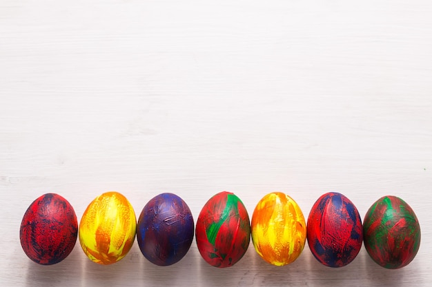Feriados, tradições e conceito de páscoa - ovos coloridos decorativos multicoloridos sobre fundo branco com espaço de cópia. vista do topo. Foto Premium