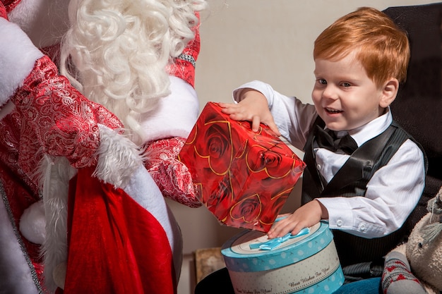 Férias, celebração, infância e conceito de pessoas. menino sorridente com o papai noel