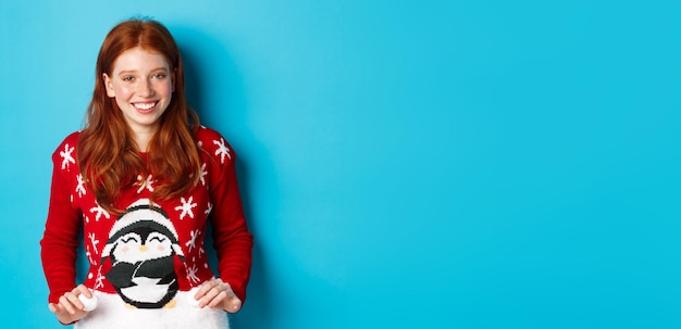 Foto grátis férias de inverno e conceito de véspera de natal linda ruiva vestindo suéter adorável e cel sorridente