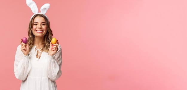 Férias de primavera e conceito de festa Retrato de linda loira alegre em orelhas de coelho segurando ovos coloridos comemorando a Páscoa com a família desfrutando de passar o dia tradicional com pessoas próximas