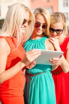 Férias e conceito de turismo - lindas garotas loiras viajam olhando para tablet pc na cidade