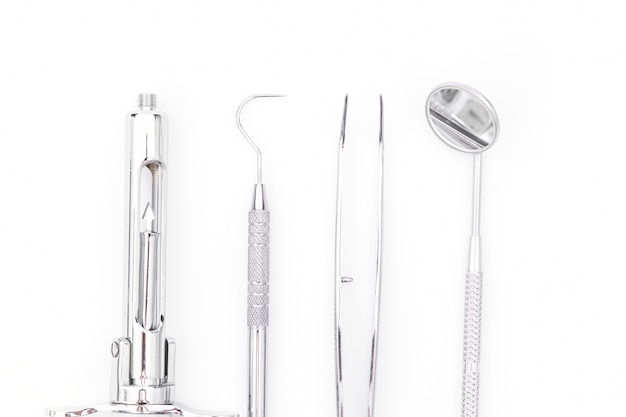 Ferramentas e equipamentos dentais no fundo branco.