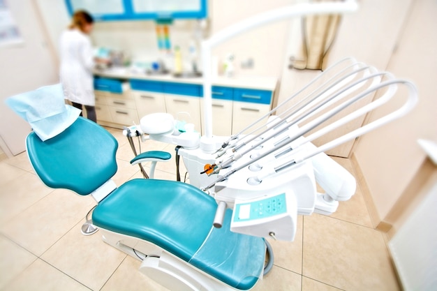 Ferramentas profissionais de dentista e cadeira no consultório odontológico.