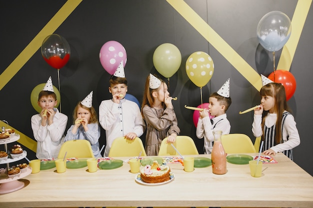 Festa de aniversário engraçada infantil no quarto decorado. Crianças felizes com bolo e balões.