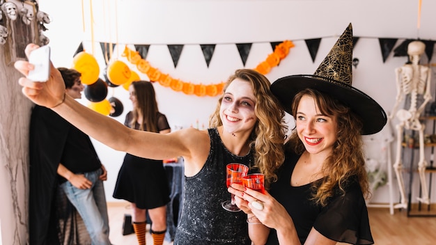 Festa de Halloween com bruxa e zumbi fazendo selfie