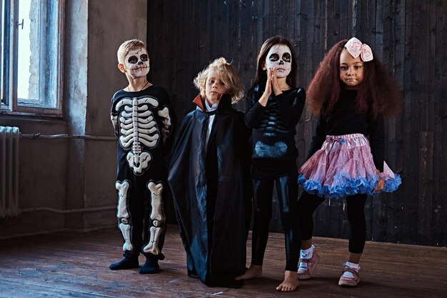 Festa de Halloween com crianças do grupo que se sentam juntas em um piso de madeira em uma casa velha