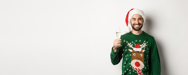 Festa de natal e conceito de feriados homem barbudo bonito com chapéu de papai noel e suéter engraçado bebendo ch