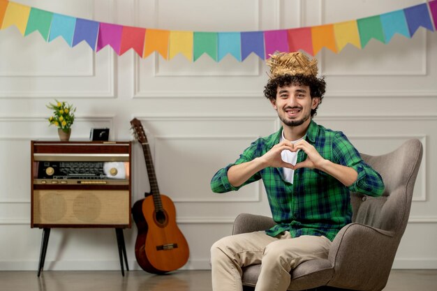 Festa junina bonitinho de chapéu de palha com rádio retrô e bandeiras coloridas mostrando sinal de coração