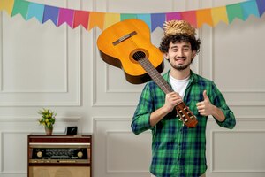 Foto grátis festa junina bonitinho de chapéu de palha com rádio retrô e bandeiras coloridas segurando guitarra no ar