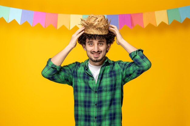 Festa junina jovem bonitinho com chapéu de palha e bandeiras coloridas festival brasileiro segurando chapéu