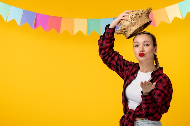 Festa junina loira linda garota no festival brasileiro de chapéu de palha com bandeiras coloridas mandando beijos
