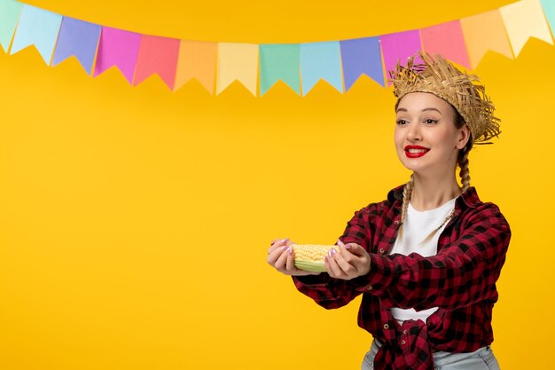 Festa junina loira linda garota no festival brasileiro de chapéu de palha com bandeiras coloridas segurando milho