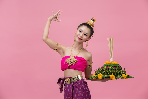 Festival Loy Krathong; mulher com roupa tradicional tailandesa segurando um flutuador decorado