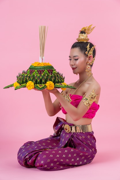 Foto grátis festival loy krathong; mulher com roupa tradicional tailandesa segurando um flutuador decorado