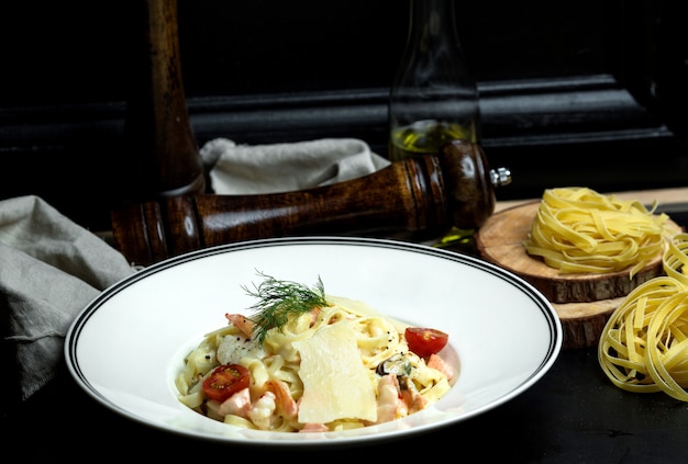 Fettuccini de frutos do mar com molho cremoso, parmesão coberto com tomate cereja e endro