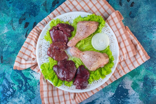 Fígado de frango, folhas de alface e coxinha de frango em um prato sobre o pano de prato